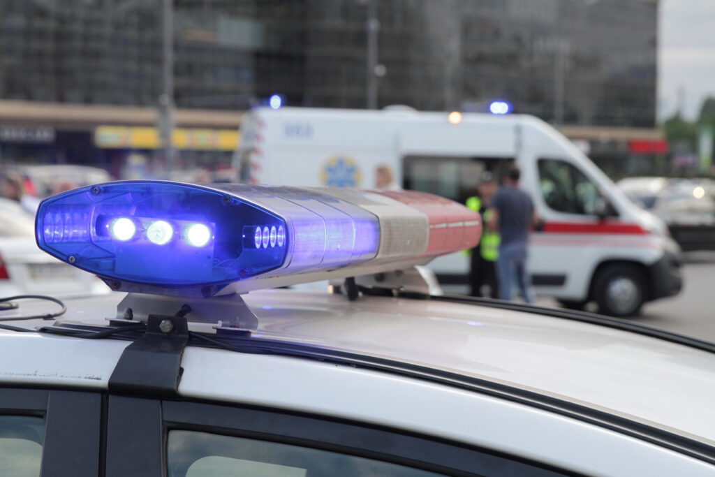 Blue light flasher atop of a police car. City lights on the background. Blue light flasher atop a police car. City lights and EMT van in the background.