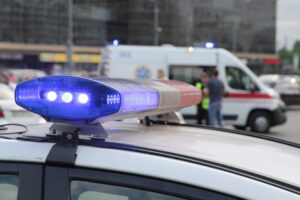 Blue light flasher atop of a police car. City lights on the background. Blue light flasher atop a police car. City lights and EMT van in the background.