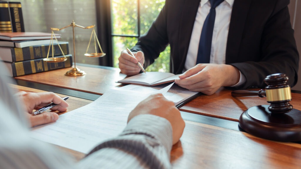 Lawyer working with client discussing contract papers with brass scale about legal legislation in courtroom, consulting to help their customer Lawyer working with client discussing contract papers with brass scale about legal legislation in courtroom, consulting to help their customer