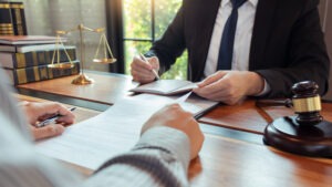 Lawyer working with client discussing contract papers with brass scale about legal legislation in courtroom, consulting to help their customer Lawyer working with client discussing contract papers with brass scale about legal legislation in courtroom, consulting to help their customer